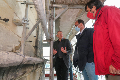 Der verantwortliche Architekt, Herr Wissmann, erläutert René Röspel und Stephan Langhard die Schäden am Mauerwerk der Christuskirche.